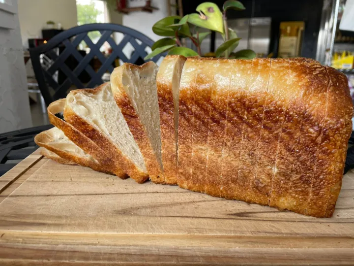 A sliced loaf of sourdough bread on a wooden board at Bread Garden Bakery.